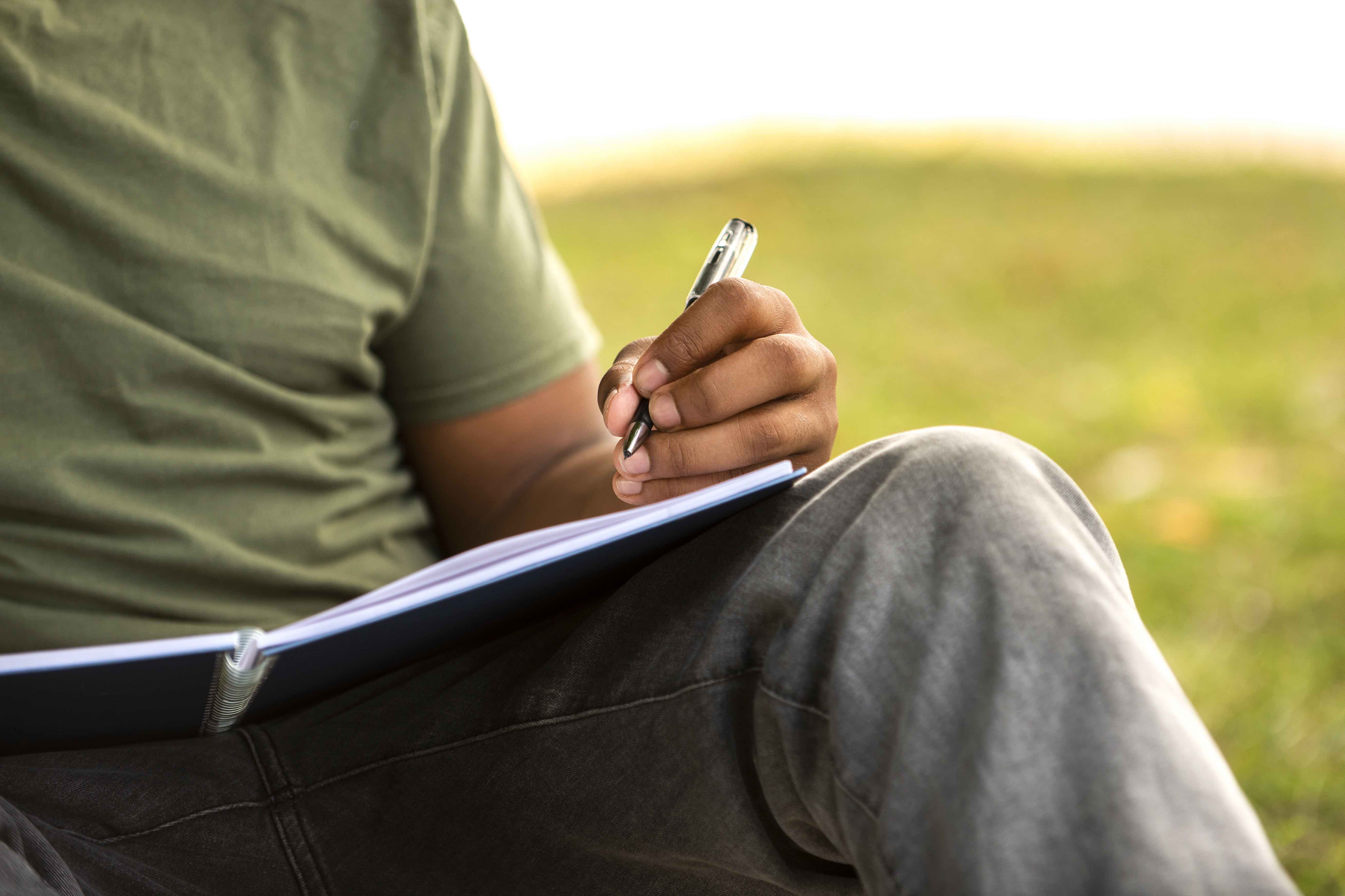 Close-up of hand writing in notebook.